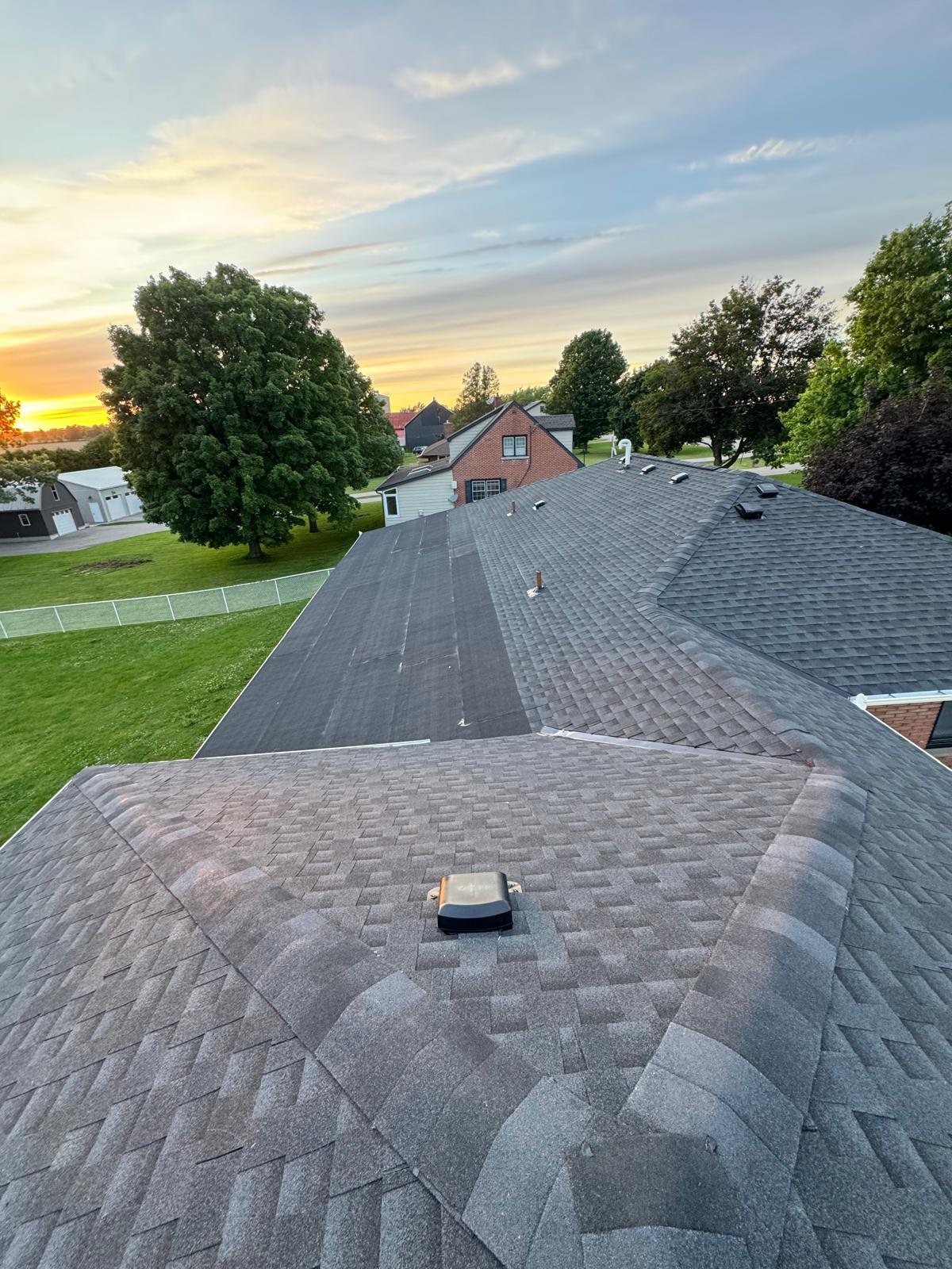 Completed grey residential shingle roof at sunset